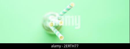 https://l450v.alamy.com/450v/2erth77/pile-of-paper-striped-white-and-green-drinking-straws-for-party-in-clear-glass-cup-on-green-background-banner-2erth77.jpg