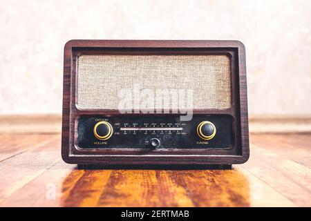 Retro vintage radio. Music nostalgia with old 60s style song player. Dusty speaker and receiver on wood. Knobs and frequency tuner, front view. Stock Photo