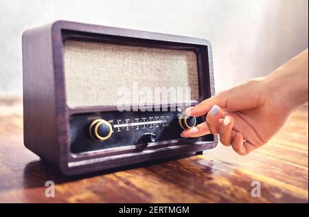 Retro radio tuning. Woman using old vintage music equipment. Adjusting volume or frequency tuner knob. Turning on or off stereo receiver or speaker. Stock Photo