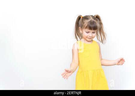 emotional little girl in yellow dress posing on grey background Stock Photo