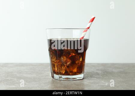 Glass of cola with ice cubes and straw on gray table Stock Photo