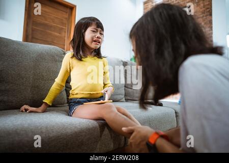 asian mother treating injured daughter with antiseptic at home Stock Photo