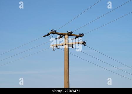 Concrete electric pole with ceramic insulators and voltage lines, in ...