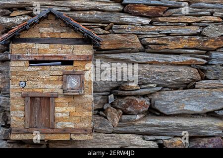 Miniature rural country house for use as a mailbox for letter correspondence on a rustic wall with brown tones Stock Photo