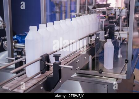 White bottles on conveyor belt of liquid filling machine Stock Photo