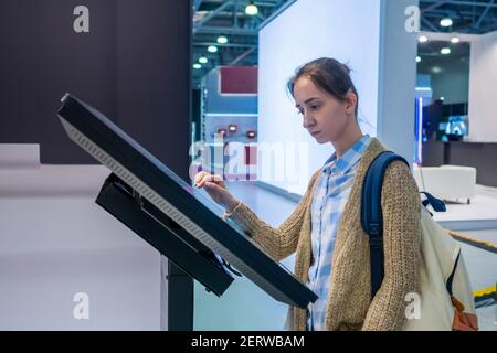 Woman using information black kiosk at exhibition at exhibition, Stock Photo