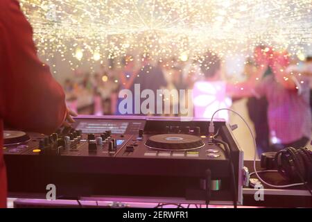 Mixing console is played by DJ and couples dancing on the dance floor in the background and empty space for text Stock Photo