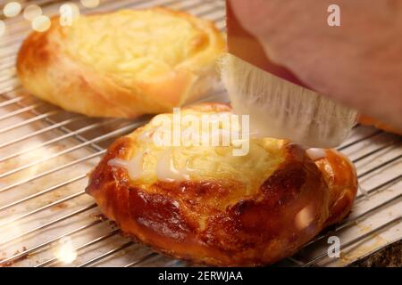 Confectioner puts the icing on the bun cake and empty space for text Stock Photo