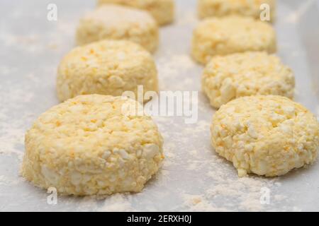 Lots of cottage cheese pancakes on a white tray with flour close up before frying in a frying pan. Selective Focus Stock Photo