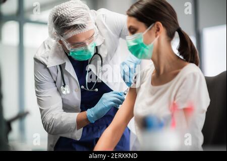 A young medical student injects a coronavirus vaccine into a young girl's shoulder Stock Photo