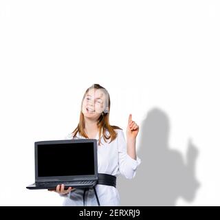 A contented blonde holds a laptop computer and points her finger up at an empty space where your text or advertisement could be. Idea on a white Stock Photo