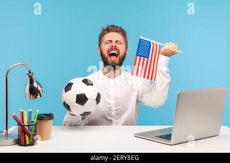 Bearded businessman cheering for favourite football team, holding horn and  ball in hands, looking smiling at camera, wearing striped shirt. Indoor  studio shot isolated on blue background Stock Photo - Alamy