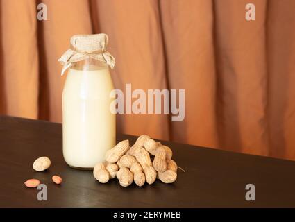 Glass bottle with peanut milk and peanuts in the shell. Lactose-free milk, vegetarianism. Stock Photo