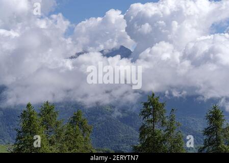 Cumulus clouds revealing the Alpine mountain range, Piedmont region, northwestern Italy Stock Photo