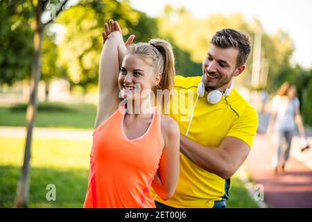 Young couple is exercising outdoor. They are and stretching and warming up for jogging. Stock Photo
