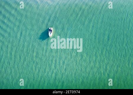 White yacht and turquoise water waves from top view. Travel summer vacations seascape background from drone