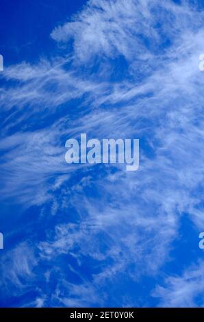 wispy white clouds on bright blue winter sky background Stock Photo