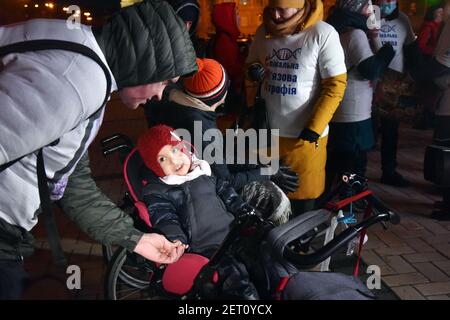KYIV, UKRAINE - FEBRUARY 28, 2021 - A child in a wheelchair is pictured during the light show in Mykhailivska Square on Rare Disease Day, Kyiv, capita Stock Photo
