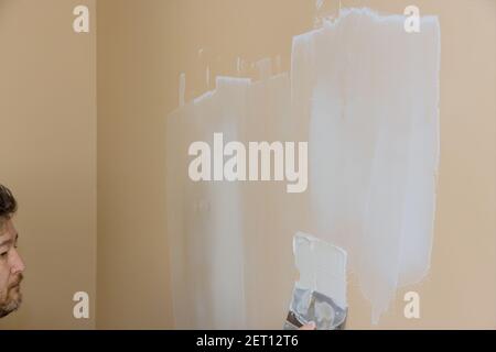 Professional construction worker applying plaster coating to the freshly plasterboard wall during room renovation Stock Photo