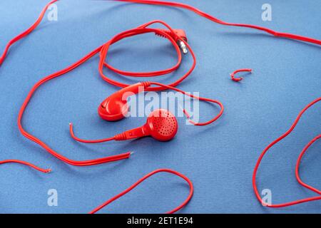 Headphones on a blue background. Torn headphones. Repair of electronic devices. Broken wire. Stock Photo