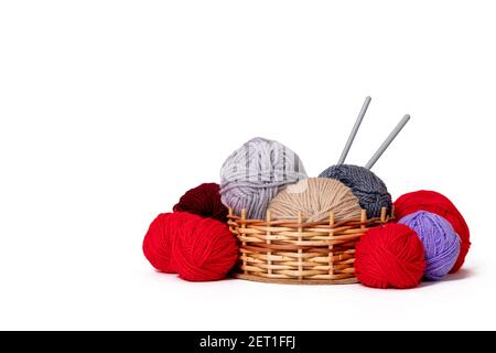 colored wool clews with needles in wicker basket. Stock Photo