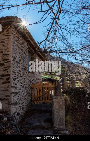 Stone house with a tree with branches and without leaves in the mountains. Stock Photo