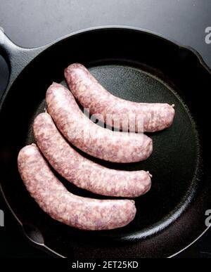 raw sausage links prior to cooking in a cast iron pan