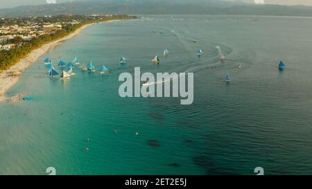 Aerial view of sailing yachts on the sandy beach of Boracay Island at sunset time. Tropical white beach with sailing boat. Summer and travel vacation concept. Stock Photo