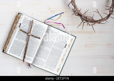 Lent border and background with cross on open bible with crown of thorns on white wood background and copy space Stock Photo