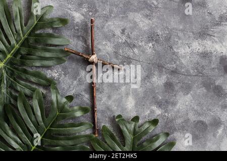 Palm leaves and wood cross on grey background Stock Photo