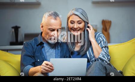 happy elderly interracial couple using laptop at home Stock Photo