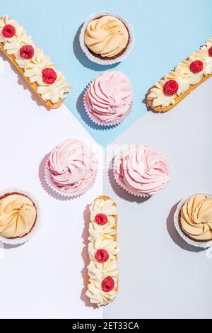 Tasty cakes in a pastel flat lay composition. Eclairs and muffins. Sweet food. Stock Photo