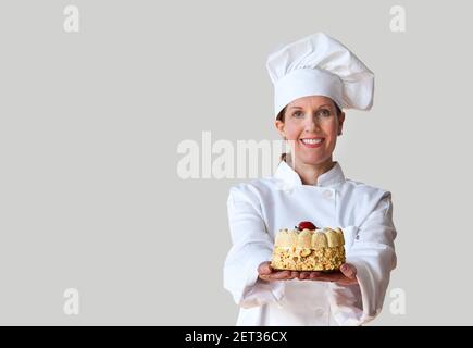 Chef holding a cake wearing a clean white chef uniform. Stock Photo