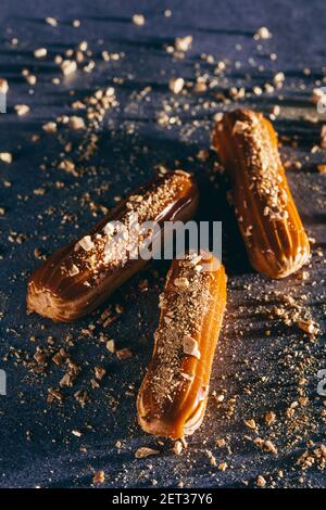 Three caramel cakes with gold sprinkles on dark background. Traditional French pastry. Top view. Stock Photo