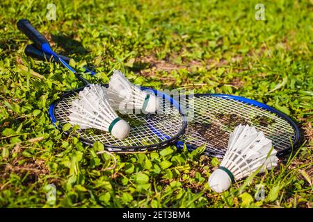Badminton rackets, shuttlecocks are lying on the grass. The concept of outdoor sports games Stock Photo