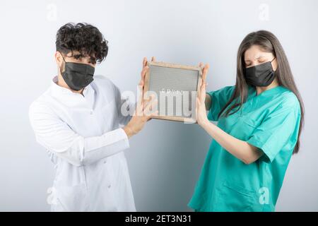Couple of doctors in uniforms holding a frame and looking at camera Stock Photo
