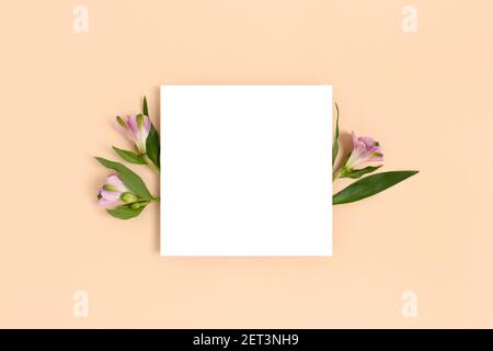 Composition with flowers and blank paper on a beige background. Greetind card mockup. Stock Photo