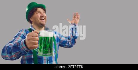 Happy man celebrating St Patrick's Day and drinking green beer on grey copy space banner Stock Photo