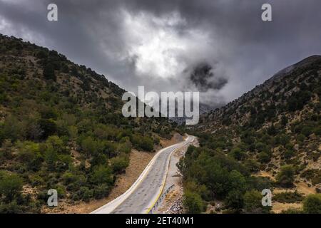 Aerial view of the road leading to the Samaria Gorge trailhead with storm clouds overhead, Crete, Greece Stock Photo