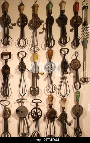 Whisks.Vintage collection of antique mechanical wooden handled food whisks, kitchenalia,  displayed as an eclectic still life, wall art. Full frame.