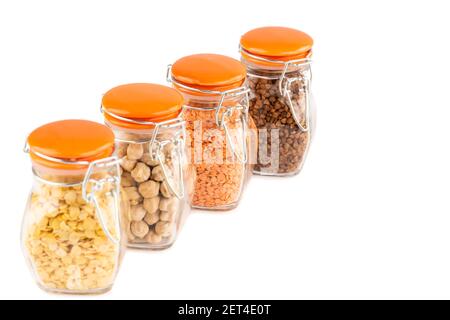 The collection of different groats in the glass jars isolated on white background. Buckwheat, chickpea and lentils. Stock Photo