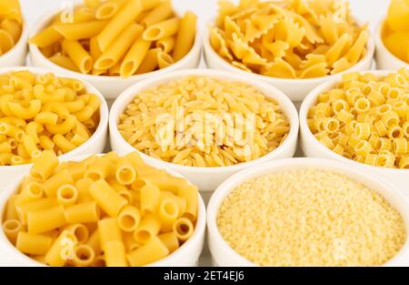 Various kind of Italian pasta in the white ceramic bowls. Stock Photo