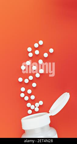 vertical photo of methyl folate tablets flying from the jar. dietary concept. dietary supplement close-up Stock Photo