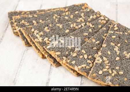 Pile of crackers with poppy and sunflower seeds on gray wooden background. Stock Photo