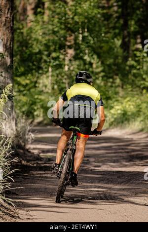 back male mountain bike rider riding on forest road Stock Photo