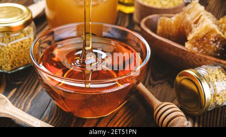 Honey in glass jar with honey dipper over wooden background Stock Photo