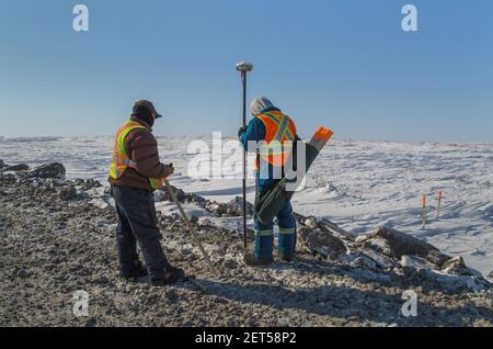Two workers surveying the Inuvik-Tuktoyaktuk Highway, winter construction, Northwest Territories, Canada's Arctic, April 2014. Stock Photo