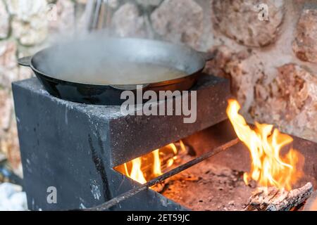 Large cauldron with freshly cooked rice. A series of the process of cooking pilaf in a huge cauldron on open fire. Frying onions and vegetables Stock Photo