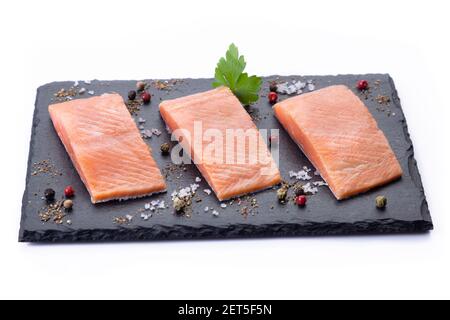 Three raw salmon filet on dark slate on white background. Stock Photo
