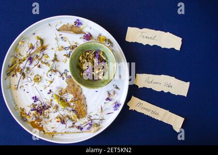 A closeup top view of ceramic dishware with torn vintage paper massages and dried flowers inside Stock Photo